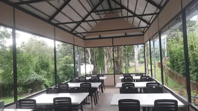 a room with tables and chairs and windows at Vipinam, The riverside retreat in Kotamangalam