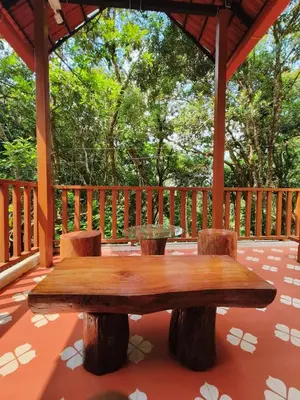 a wooden table and chairs on a deck with trees at Reevilla in Madikeri