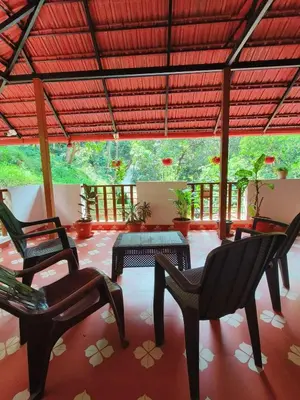 a screened in porch with chairs and a table at Reevilla in Madikeri