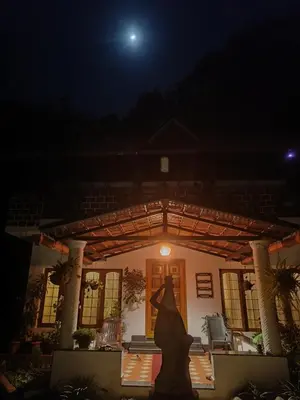 a woman in a dress standing in front of a house at night at Reevilla in Madikeri