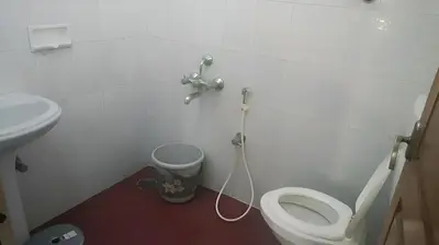a bathroom with a white toilet and a sink at Raaha Luxury Home Stay in Mysore