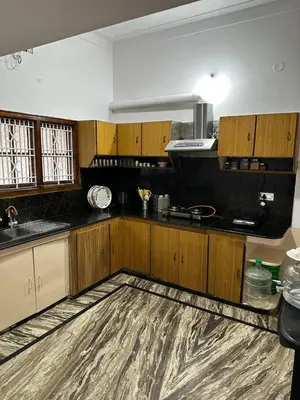 a kitchen with wooden cabinets and black counter tops at Raaha Luxury Home Stay in Mysore
