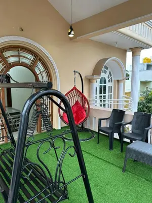 a porch with a hammock on the grass at Raaha Luxury Home Stay in Mysore