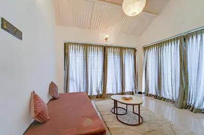 a living room with a table and some windows at Garden Haven 3 BHK Villa with Balcony and Verandah Escape in Kotagiri
