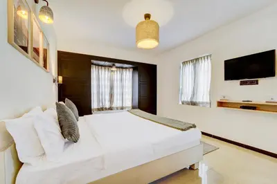 a bedroom with a white bed and a flat screen tv at Garden Haven 3 BHK Villa with Balcony and Verandah Escape in Kotagiri