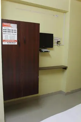 a room with a wooden cabinet with a tv on a wall at Aishvarya Residency in Coimbatore