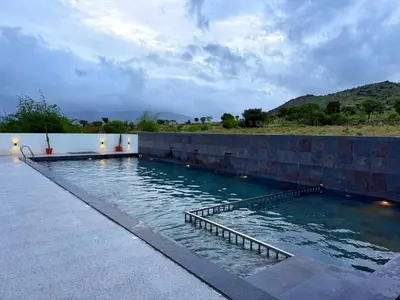 a swimming pool with a stone wall and water at Leopard Hill Resort - Bandipur in Bandipūr
