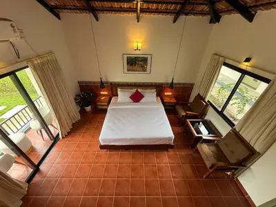 a bedroom with a bed and some windows at Leopard Hill Resort - Bandipur in Bandipūr