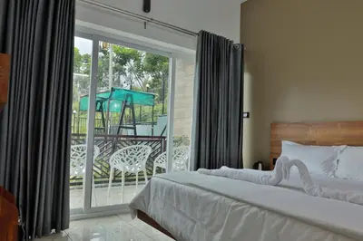 a bedroom with a bed and a balcony with a sliding glass door at Banbury Bungalow in Kanthalloor