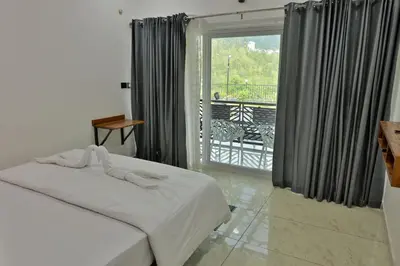 a bedroom with a bed and a view of a balcony at Banbury Bungalow in Kanthalloor