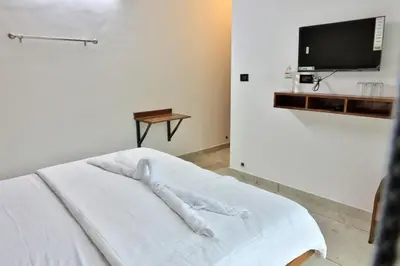 a bedroom with a white bed with a tv on the wall at Banbury Bungalow in Kanthalloor