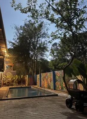 a swimming pool in front of a fence with a mural at Forest Soul by BOB Hotels - Forest Retreat with Pool in Batheri