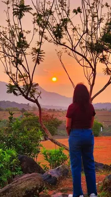 a woman standing in front of a sunset at Forest Soul by BOB Hotels - Forest Retreat with Pool in Batheri