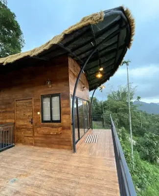 a wooden house with a roof with a deck at Jalsa Bali, Kakkadampoyil, Calicut in Kakkadampoyil