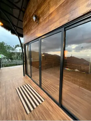 a house with glass windows and a wooden deck at Jalsa Bali, Kakkadampoyil, Calicut in Kakkadampoyil