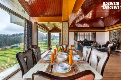a dining room with a table and chairs and a large window at The Secret Glen by VEO - Part of StayVista with BBQ & Bonfire in Ooty