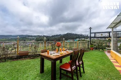 a wooden table with chairs sitting on top of a yard at The Secret Glen by VEO - Part of StayVista with BBQ & Bonfire in Ooty