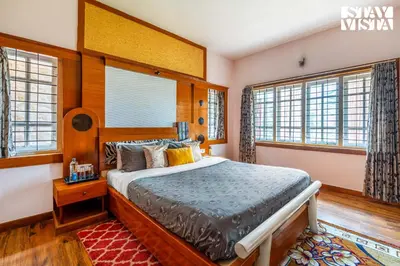 a bedroom with a large bed in a room with windows at The Secret Glen by VEO - Part of StayVista with BBQ & Bonfire in Ooty