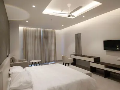 a bedroom with a white bed and a television at The Palazzo Chakolas in Trichūr