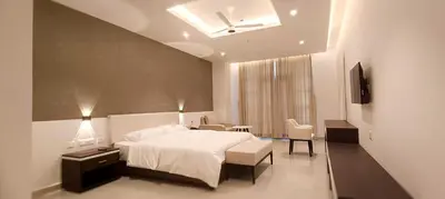 a bedroom with a white bed and a table and chairs at The Palazzo Chakolas in Trichūr
