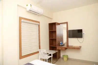 a bedroom with a desk and a window and a desk with a chair at Haaz Grande Kunnamangalam in Kunnamangalam