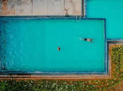 a person swimming in a large swimming pool at Whitelake Resort in Bilikere
