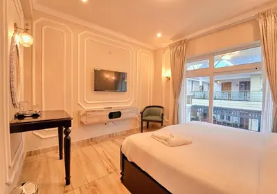 a bedroom with a bed and a desk and a window at King Palace Ooty by VOYE HOMES in Ooty