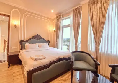 a bedroom with a bed and a chair and a window at King Palace Ooty by VOYE HOMES in Ooty