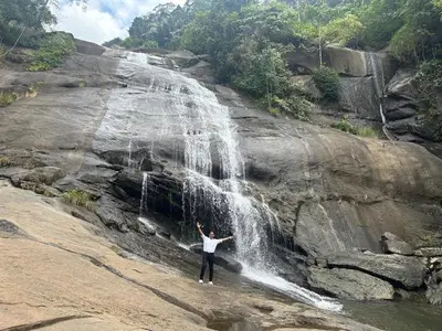 a man standing in front of a waterfall at Enhance Lifestyle Service Apartments in Thamarassery