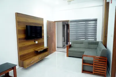 a living room with a couch and a flat screen tv at Enhance Lifestyle Service Apartments in Thamarassery