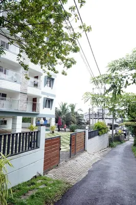 a building with a fence next to a street at Enhance Lifestyle Service Apartments in Thamarassery