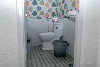 a bathroom with a toilet and a trash can at Pleasant Heights Homestay in Coonoor
