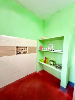 a kitchen with green walls and a red floor at GSC Family Holiday Home in Pollāchi
