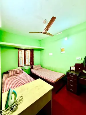 a green room with two beds and a ceiling fan at GSC Family Holiday Home in Pollāchi