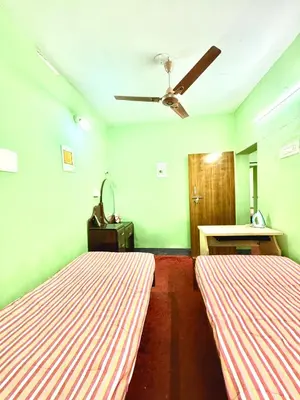 two beds in a room with green walls at GSC Family Cottage in Samattūr