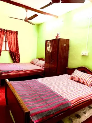 two beds in a room with green walls at GSC Family Cottage in Samattūr
