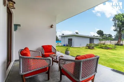 a patio with chairs and a table with a view of a yard at Stayvista at Serenova with big pvt pool and lawn - Your Luxury escape awaits ! in Madikeri