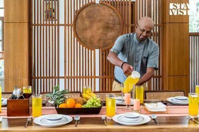a man is pouring orange juice into a table at Stayvista at Serenova with big pvt pool and lawn - Your Luxury escape awaits ! in Madikeri