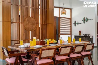 a dining room with a large wooden table and chairs at Stayvista at Serenova with big pvt pool and lawn - Your Luxury escape awaits ! in Madikeri