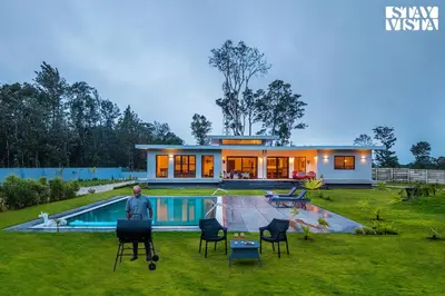 a man standing in front of a house with a pool at Stayvista at Serenova with big pvt pool and lawn - Your Luxury escape awaits ! in Madikeri