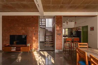 a living room with a brick wall and a tv at Tranquil Nest in Kozhikode
