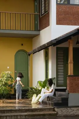a woman and a child sitting on the steps of a house at Tranquil Nest in Kozhikode