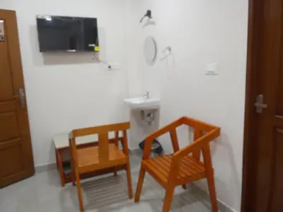 a bathroom with two wooden chairs and a sink at Benzy Tourist Home in Ponnāni
