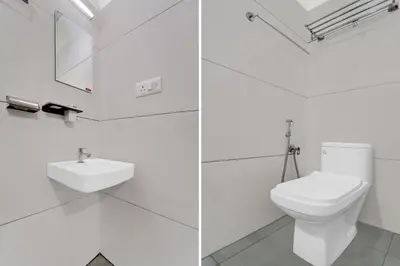 a white bathroom with a toilet and a sink at Hotel O Chalakkudy River Annamanada Svasthya Retreat in Māla