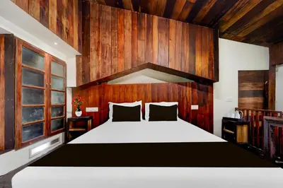 a bedroom with a large bed with a wooden wall at Hotel O Chalakkudy River Annamanada Svasthya Retreat in Māla