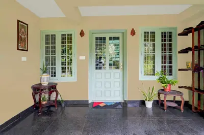 a room with two tables and a white door and windows at Hotel O Chalakkudy River Annamanada Svasthya Retreat in Māla