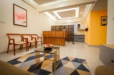 a living room with a table and chairs and a kitchen at Revoura Heights Apartments in Sultan Bathery