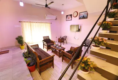 a living room with a couch and chairs and a staircase at Tranquil Rest House in Trichūr