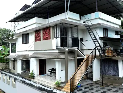 a white house with a staircase in front of it at Tranquil Rest House in Trichūr
