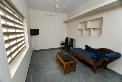 a living room with a blue couch and a table at Tranquil Rest House in Trichūr